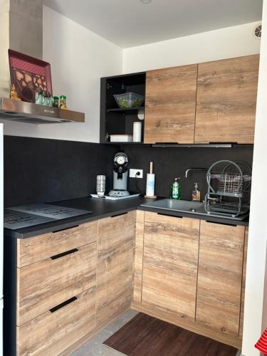 a kitchen with wooden cabinets and a sink at Appartement cosy avec jardin in Nyons