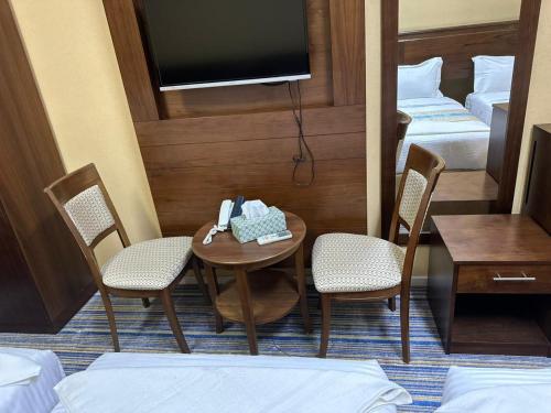 a room with a table and two chairs and a television at فندق نجمة ذاخر توصيل مجاني للحرم - Zakher Star Hotel Free Shuttle Service in Makkah