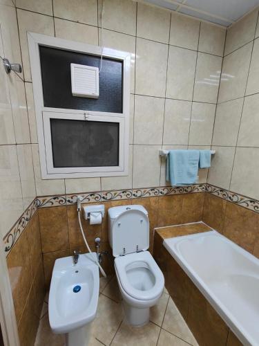 a bathroom with a toilet and a sink and a tub at Delightful 3Bedroom Family Apartment with Garden View in Sharjah