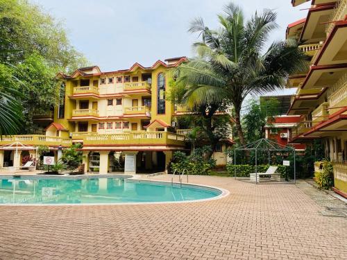 a hotel with a swimming pool in front of a building at Candolim Beach Apartments Goa in Candolim