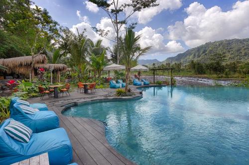 una piscina in un resort con sedie e tavoli blu di Natya River Sidemen a Sidemen