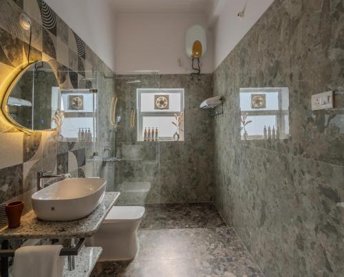 a bathroom with a sink and a toilet and a mirror at SaffronStays Sher Bagh - 4BR eco-friendly pool villa with jungle trails, farm-to-table meals & bonfire nights near Corbett Park in Belparāo