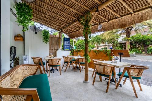 a restaurant with tables and chairs under a straw umbrella at Bali Bay by Urban Haven in Sanur