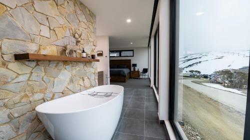 a bathroom with a stone wall and a white tub at Whitemount in Mount Hotham
