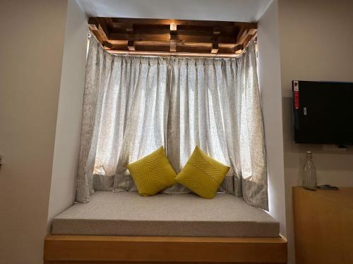 a window seat with two yellow pillows in a room at Maple house ladakh in Leh