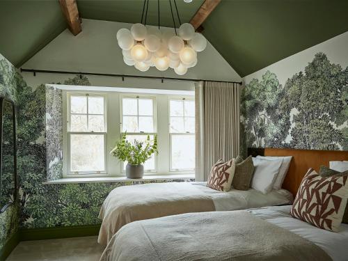 a bedroom with two beds and a window and a chandelier at Eskdale Retreat in Holmrook