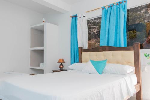 a bedroom with a large bed with blue curtains at Hotel Manakin Tayrona in El Zaino