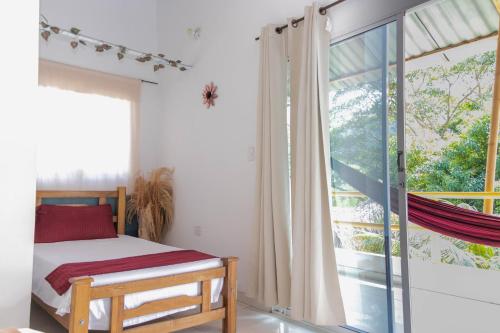 a bedroom with a bed and a large window at Hotel Manakin Tayrona in El Zaino