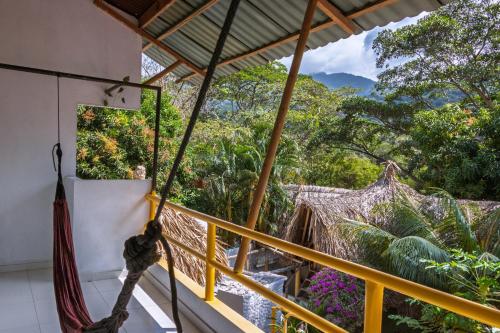 a hammock on a balcony with a view of the jungle at Hotel Manakin Tayrona in El Zaino