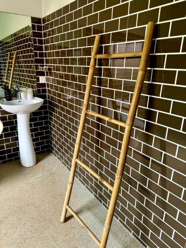 a wooden ladder in a bathroom next to a sink at Mes trois coeurs in Phumĭ Réach Born
