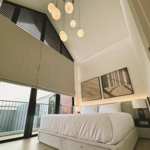 a bedroom with a large bed and large windows at Cerita di Villa - Your Second Home in Batu in Tlekung