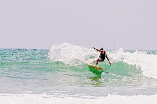 a man riding a wave on a surfboard in the ocean at Coco Inn Polhena in Matara