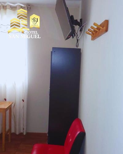 a room with a red chair and a tv on a wall at Hotel San Miguel in San Miguel