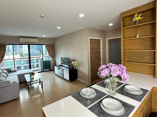 a living room with a table with a vase of flowers at convenient&peaceful place in Soi nai leot in Bangkok