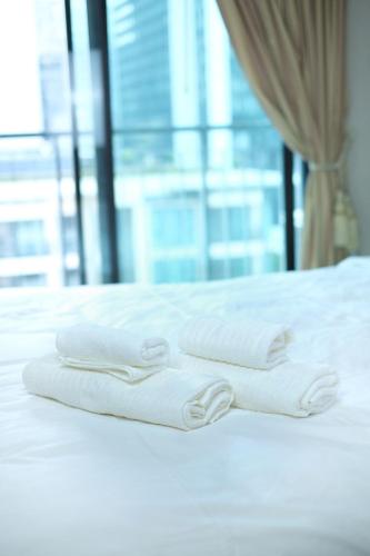 three white towels sitting on top of a bed at convenient&peaceful place in Soi nai leot in Bangkok