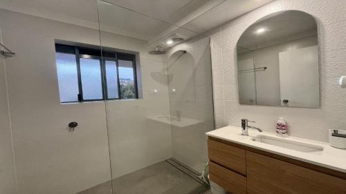 a bathroom with a shower and a sink and a mirror at Sandy Cove Unit 6 in Caloundra