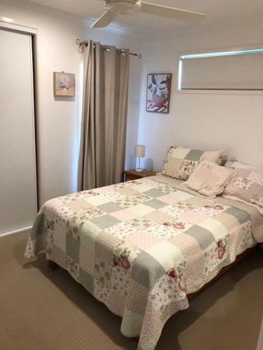 a bedroom with a bed with a quilt on it at The Cottage in Tingoora