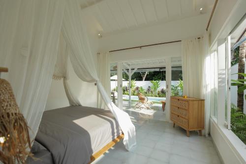 a bedroom with a canopy bed and a balcony at The Bingin Beach Villas' Private Villas in Uluwatu