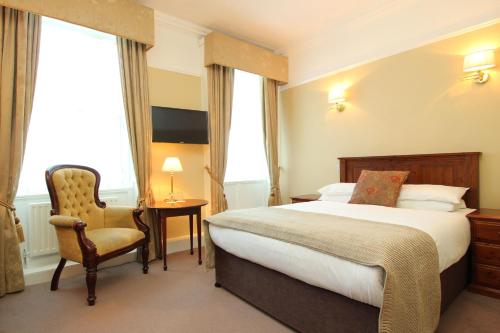 um quarto de hotel com uma cama e uma cadeira em Castle Hotel em Dublin