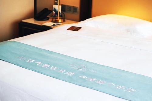 a bed with a blue ribbon on the side of it at The Yun Hotel Foshan Nanhai-Near Pazhou Complex in Foshan