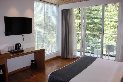 a hotel room with a bed and a large window at Moksha Riverside Resort in Kasol
