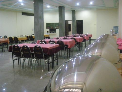 a room filled with tables and chairs with pink table cloth at Dena Hotel in Soe