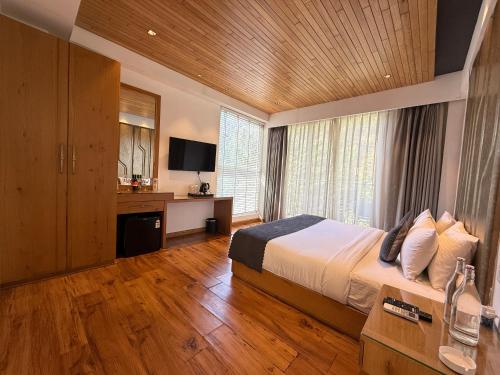 a bedroom with a bed and a desk and a television at Moksha Riverside Resort in Kasol