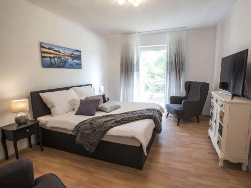 a bedroom with a bed and a tv and a chair at Comfortable holiday residence in Keutschach am See