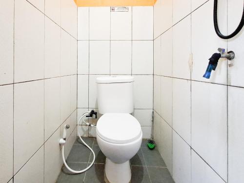 a bathroom with a toilet in a white tiled wall at Labella Homestay 1 Syariah Dieng RedPartner in Dieng