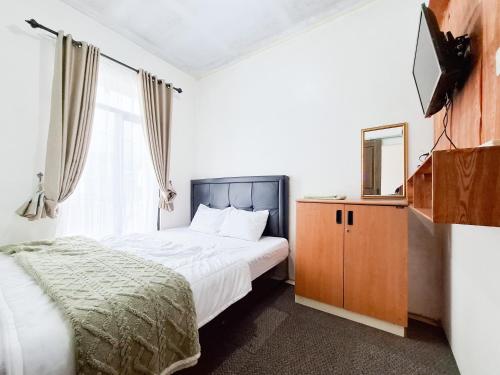 a bedroom with a bed and a dresser and a mirror at Labella Homestay 1 Syariah Dieng RedPartner in Dieng