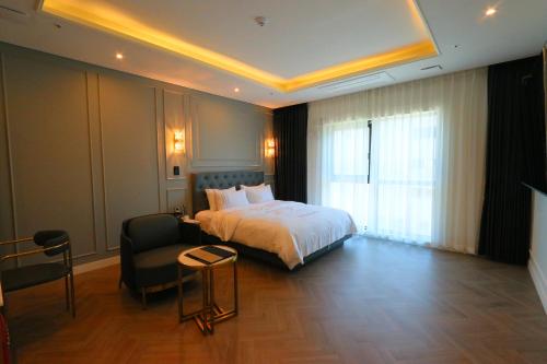 a hotel room with a bed and a chair at Mokpo Caltonhill Hotel in Mokpo