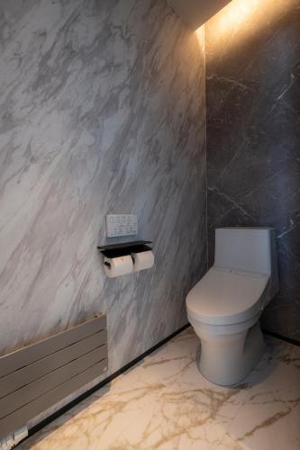 a bathroom with a toilet and two rolls of toilet paper at HIGASHIKAWA Villa 森音 in Higashikawa