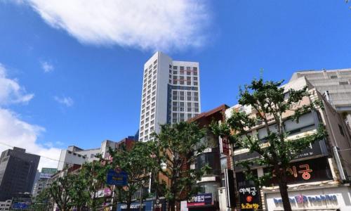 a tall white building in the middle of a city at Yeonsan The Stay in Busan