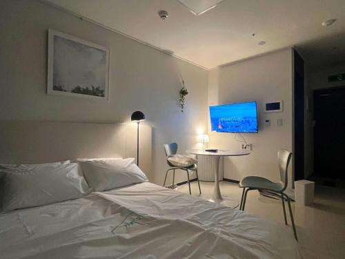a bedroom with a bed and a table and a tv at Yeonsan The Stay in Busan