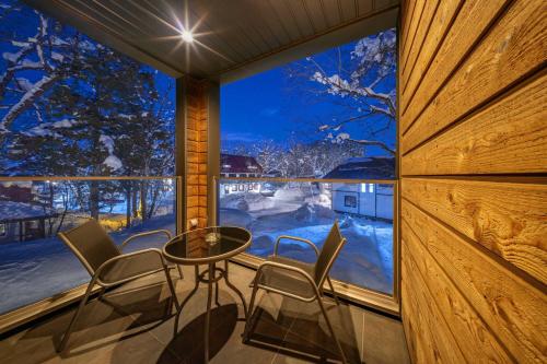 a balcony with a table and chairs in front of a window at Bluebird Chalets by The Hakuba Collection in Hakuba