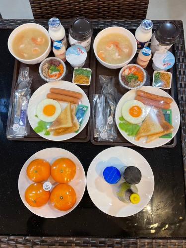 a tray of food with eggs and oranges on plates at Sawasdee​ Buriram​ Resort in Buriram
