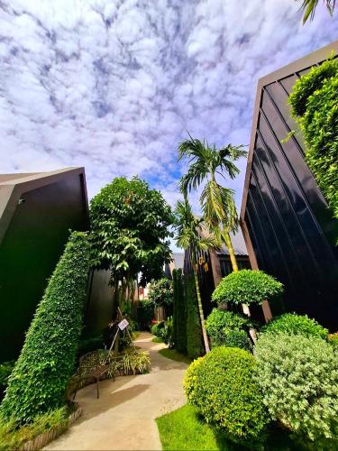 a garden with bushes and trees next to a building at Sawasdee​ Buriram​ Resort in Buriram