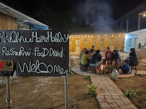 a group of people sitting around a fire in front of a building at Mai Chau Home Holiday in Mai Chau