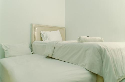 two beds with white sheets and pillows in a bedroom at Comfort Studio Apartment Aeropolis Residence By Travelio in Tangerang