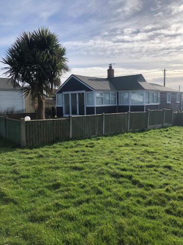 a house with a fence and a palm tree at The Beach House in Bacton