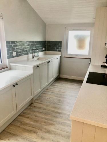 a kitchen with white cabinets and a sink and a window at The Beach House in Bacton