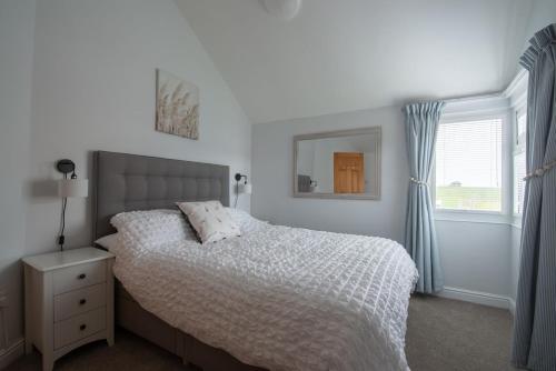 a bedroom with a white bed and a window at The Beach House in Bacton
