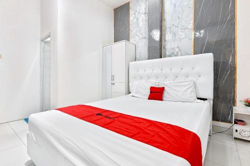 a bedroom with a large white bed with a red blanket at RedDoorz Near RS UMMI Bogor in Slada