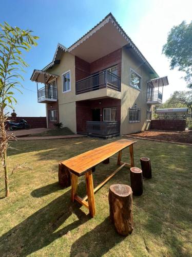 a wooden bench in front of a house at Omkar Villa in Kelghar