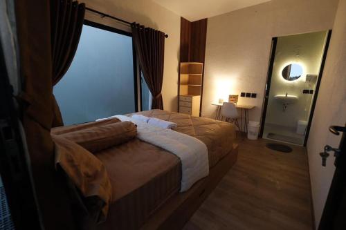 a bedroom with a bed and a large window at Villane Tumpeng in Giripurno