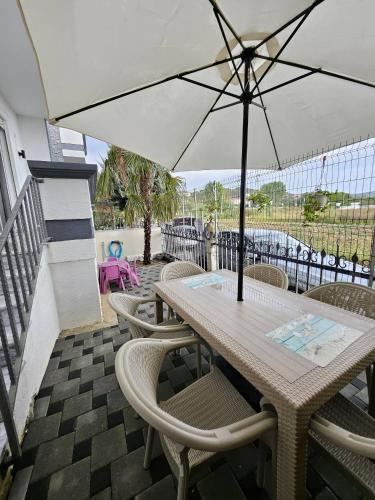 a table and chairs with an umbrella on a patio at Charming 2A Holiday House Apartment with Garden and BBQ in Fushë-Draç