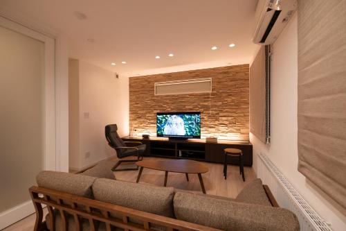 a living room with a couch and a table and a tv at Tokuno Zoo Street in Asahikawa