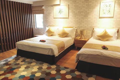 a hotel room with two beds and a rug at Sojourn Spa Hotel in Kuala Lumpur