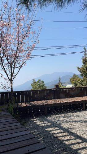a wooden bench sitting next to a fence with a tree at Home Box in Renai