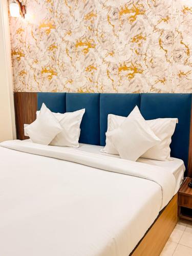 a bed with white pillows in a room with a wall at The Blue Vista in Greater Noida